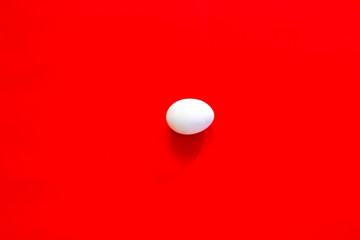 Fototapeta na wymiar White egg on the red background in center.