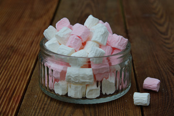 White and pink mini marshmallows in glass bowl on wooden background. Selective focus.
