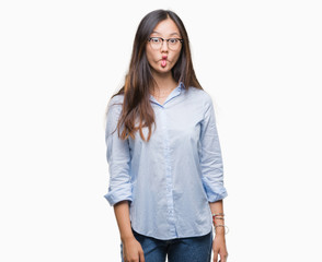 Fototapeta premium Young asian business woman wearing glasses over isolated background making fish face with lips, crazy and comical gesture. Funny expression.