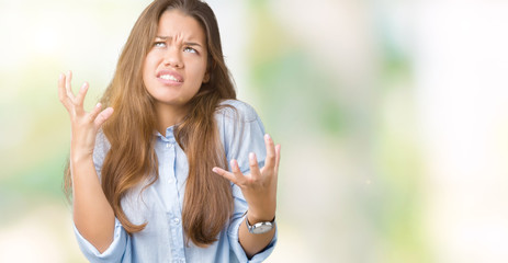 Young beautiful brunette business woman over isolated background crazy and mad shouting and yelling with aggressive expression and arms raised. Frustration concept.