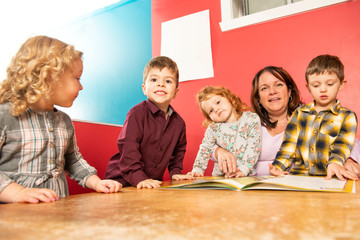 The cute preschoolers group in kindergarten together read a book
