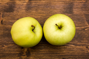 Two yellow apples on a wooden table viewed from above