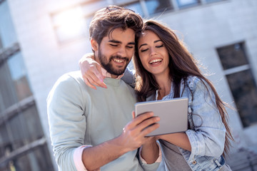 Cheerful couple using digital tablet outdoors