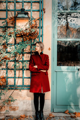 Style redhead girl in red coat stay near vintage house in Versailles, France