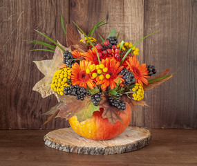 Autumn bouquet in a vase made out of pumpkin for Thanksgiving Day.