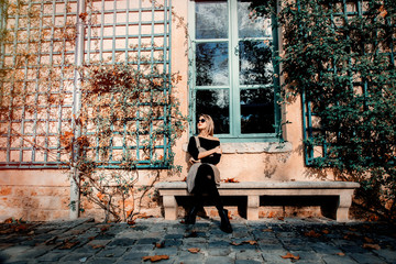 Young girl in dress and black clothes near house in Versailles, France. Autumn season time.