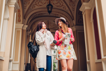 Two women tourists talking while going sightseeing in Odessa. Happy friends travelers using map
