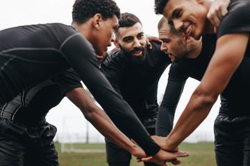 Football players in a huddle holding hands - Powered by Adobe