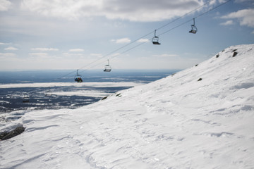 Obraz premium Shiny snow with blurred ski-lift cable car and mountain range. Copy space