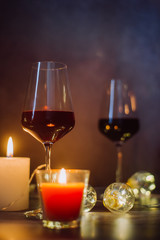 Holidays composition made of glass of red wine, candles and garlands on a dark background