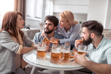 Group of friends enjoying pizza and beer