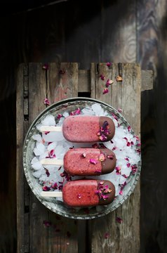 Homemade cherry and rose mangnums with a drak chocolate tip, on a dark wooden background