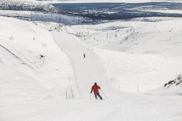 Fototapeta na wymiar Skiers skiing downhill in high mountains, rear view, Kirovsk, Russia