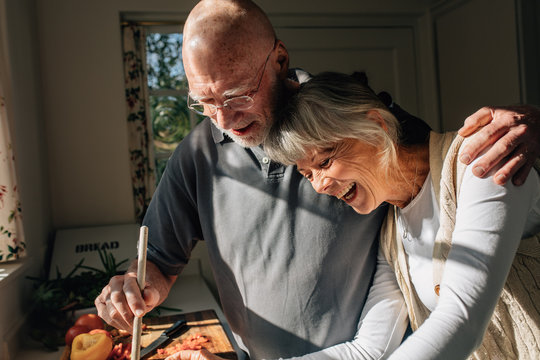 Senior couple cooking food together standing in kitchen