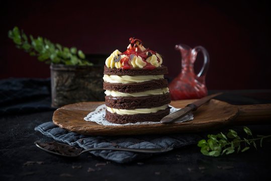 Cream cake with strawberry sauce served on wooden board