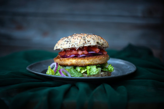 Vegan chia bread roll with a turnip escalope, tomatoes, red onions and lettuce
