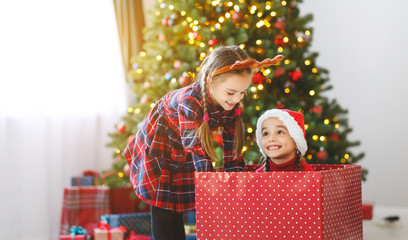 Obraz na płótnie Canvas happy children girls with christmas gifts near tree in morning