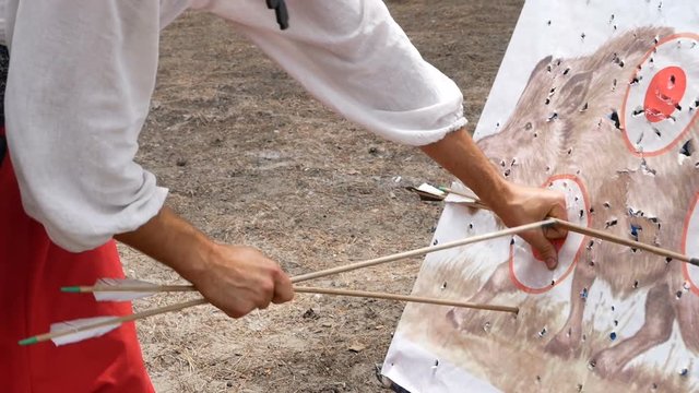 man in a national Ukrainian costume kozak pulls arrows from a target
