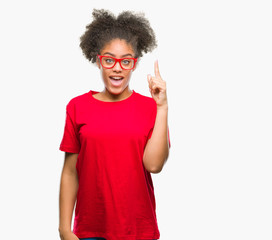 Young afro american woman wearing glasses over isolated background pointing finger up with successful idea. Exited and happy. Number one.