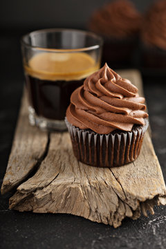 Dark chocolate cupcake with ganache frosting, espresso in glass