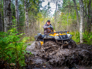 ATV overcomes the swamp. A man travels on ATV. Yellow quad bike. Off-road travel. A man drives an SUV. Yellow ATV. © Grispb