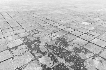 Full frame background of old and weathered cement paving slabs outdoors in black and white.