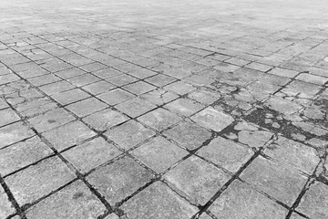 Full frame background of old and weathered cement paving slabs outdoors in black and white.