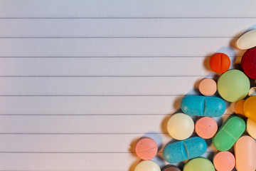 Pills and colored capsules on a neutral striped background.