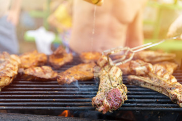 Friends frying the meat ribs and steaks, process close up. Barbecue on open air, weekend rest