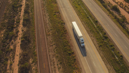 AERIAL: Cars and transportation semi trucks driving on busy highway - obrazy, fototapety, plakaty