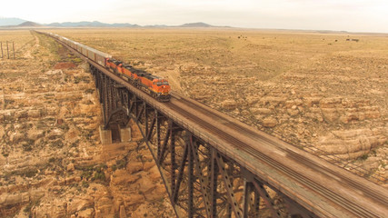 AERIAL: Two trains crossing steel arch railroad bridge across the Canyon Diablo