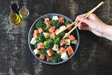 Poke bowl with salmon. Salmon broccoli sesame poke. Top view. Food sticks.