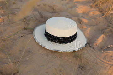 Fototapeta na wymiar hat on sand. straw hat. sand. summer. women's white hat