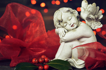 Angel and Christmas holly with Christmas lights in background