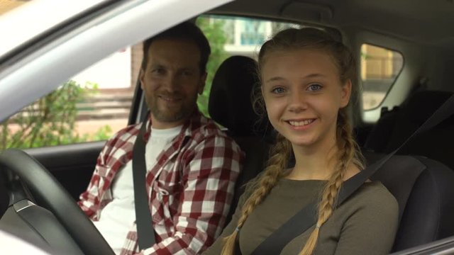 Happy female smiling into camera, sitting in car with instructor, driving school