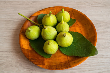 Green figs on a leaf in a wooden tray