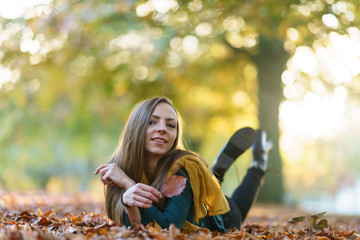 Young woman lying down on the ground in a park in autumn