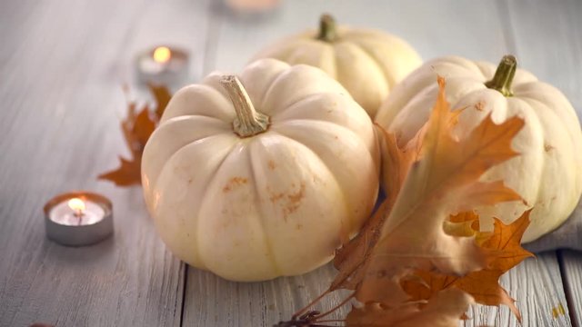 Thanksgiving holiday scene. Wooden table, decorated with pumpkins, autumn leaves and candles. 4K UHD video footage. Slow motion 3840X2160