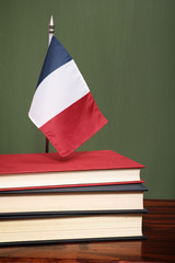 Books and French flag in front of a green chalkboard
