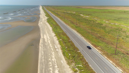 AERIAL: Black SUV car driving on countryside road along the Bay of Mexico