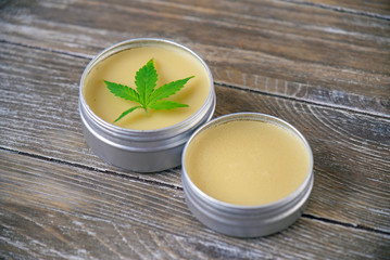 Cannabis hemp cream with marijuana leaf over wood backgroun