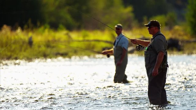 Fisherman using rod and reel fly fishing in freshwater river USA