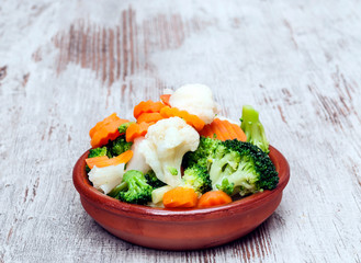 Vegetables served on a plate surrounded byrustic background