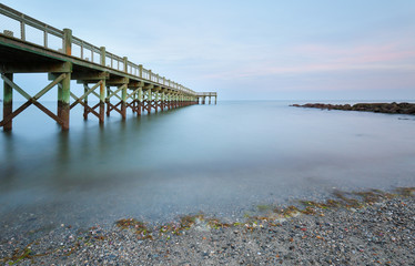 Overview of beautiful fishing pier after sunset at low tide at Walnut Beach, Milford Connecticut,...