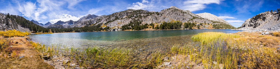 Obraz premium Panoramic view of alpine lake surrounded by the rocky ridges of the Eastern Sierra mountains; Long Lake, Little Lakes Valley trail, John Muir wilderness, California