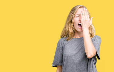 Beautiful young woman wearing oversize casual t-shirt over isolated background Yawning tired covering half face, eye and mouth with hand. Face hurts in pain.