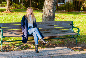 Beautiful girl sitting on bench in autumn in the park
