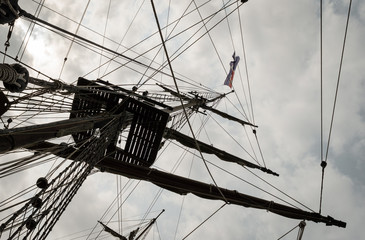 The mast and rigging of a old ship sailboat against a cloudy sky.. Element of the yacht. Mast of...
