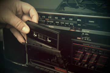 Fototapeta premium Mężczyzna wkłada kasetę do starego zakurzonego magnetofonu