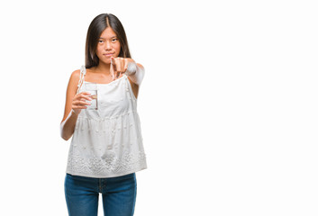Fototapeta premium Young asian woman drinking glass of water over isolated background pointing with finger to the camera and to you, hand sign, positive and confident gesture from the front
